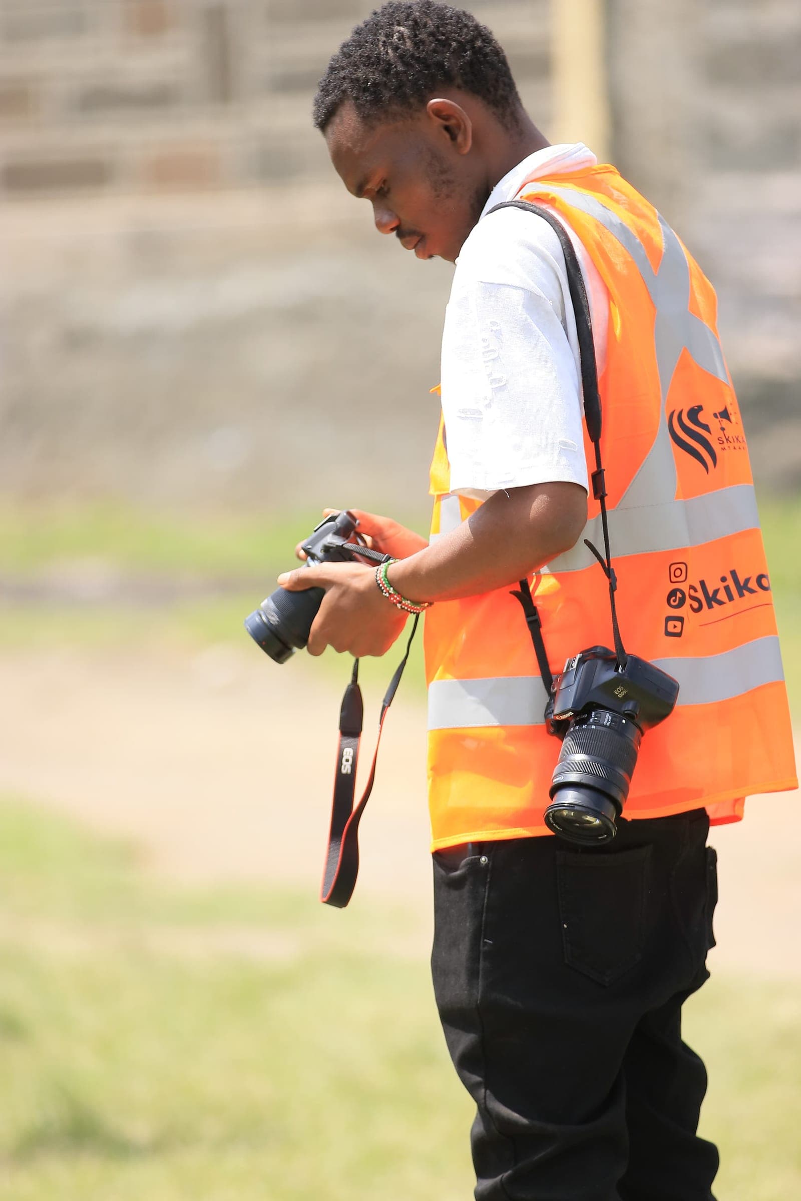 Photographer in a hi-vis vest reviewing shots with two cameras at an event