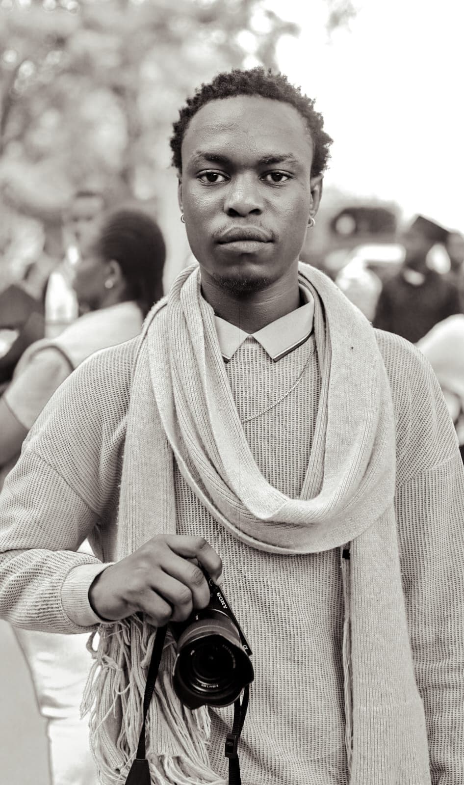 Black and white portrait of a photographer in a scarf holding a Sony camera