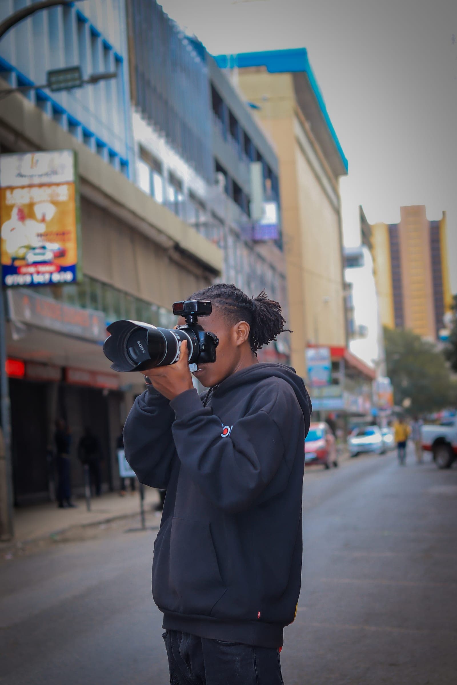 Photographer with locs shooting with a telephoto lens on a Nairobi CBD street