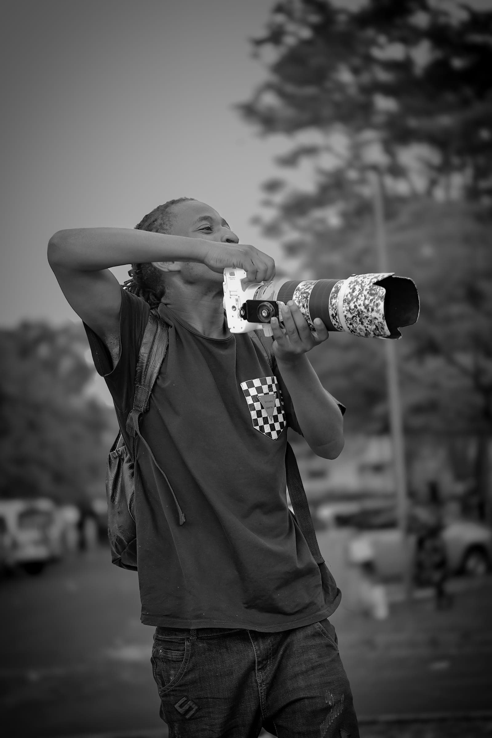 Black and white photo of a photographer aiming a long white telephoto lens