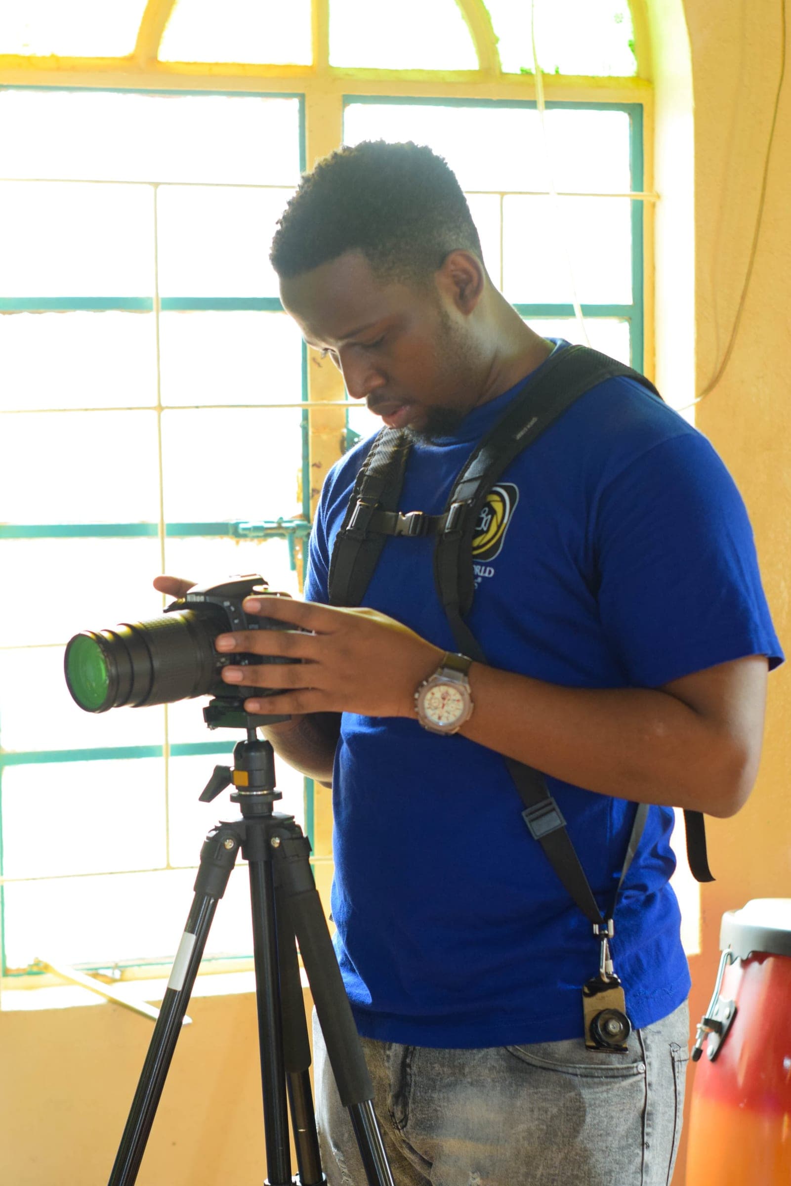 Videographer setting up a Nikon camera on a tripod by a sunlit window